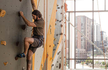 male student climbing rock wall