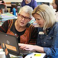 Two female teachers working together on a laptop.